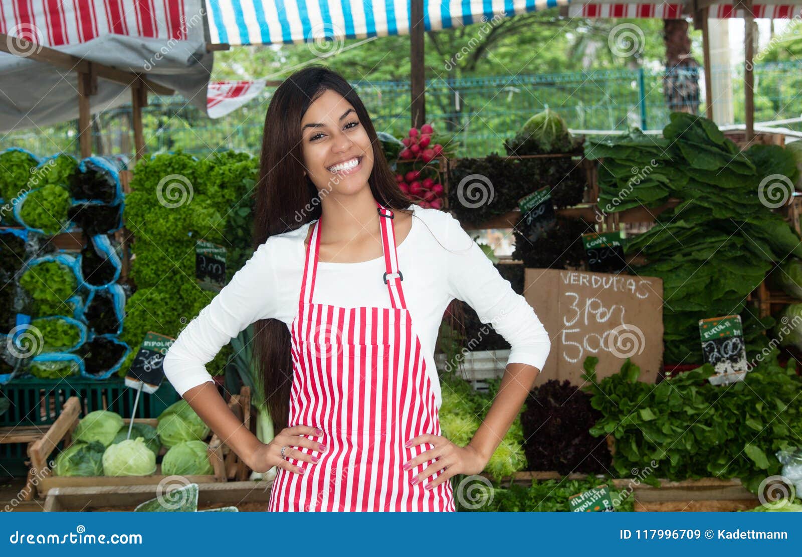 latin american woman selling vegetables and salad at farmers mar