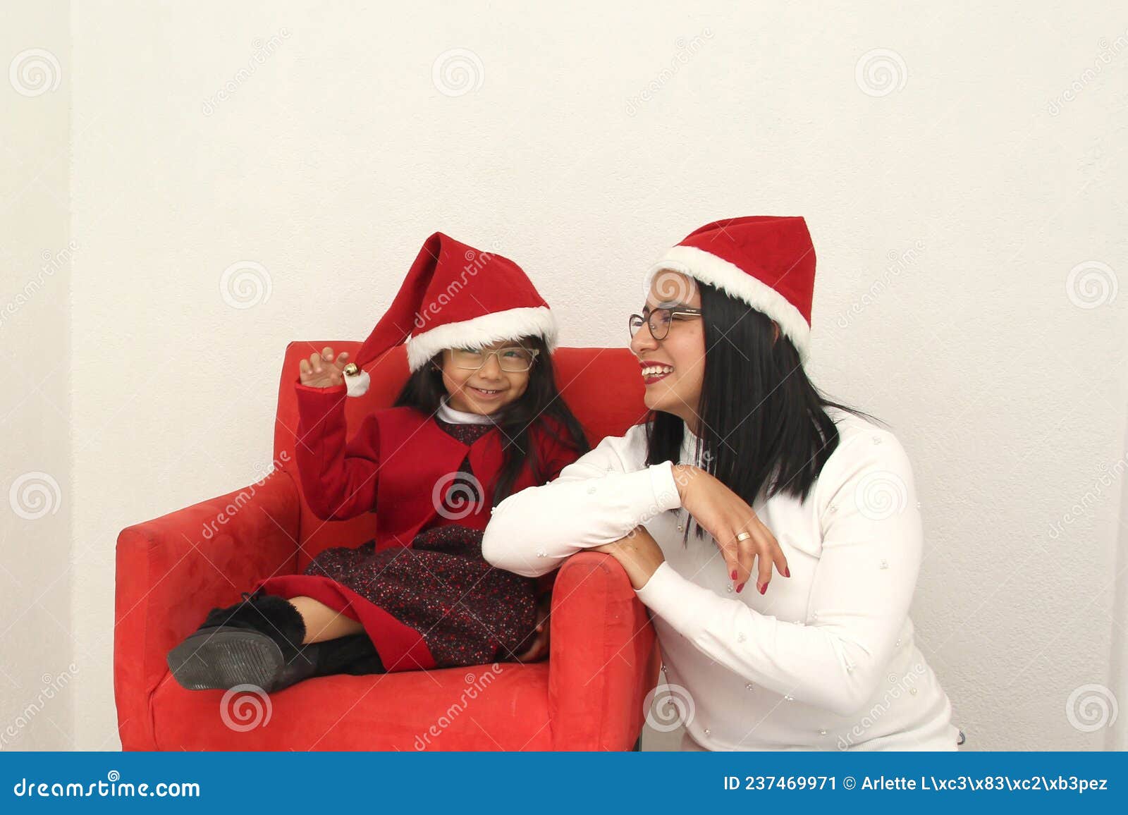 Latina Mom And Daughter With Glasses Hat And Christmas Garland Show Their Enthusiasm And