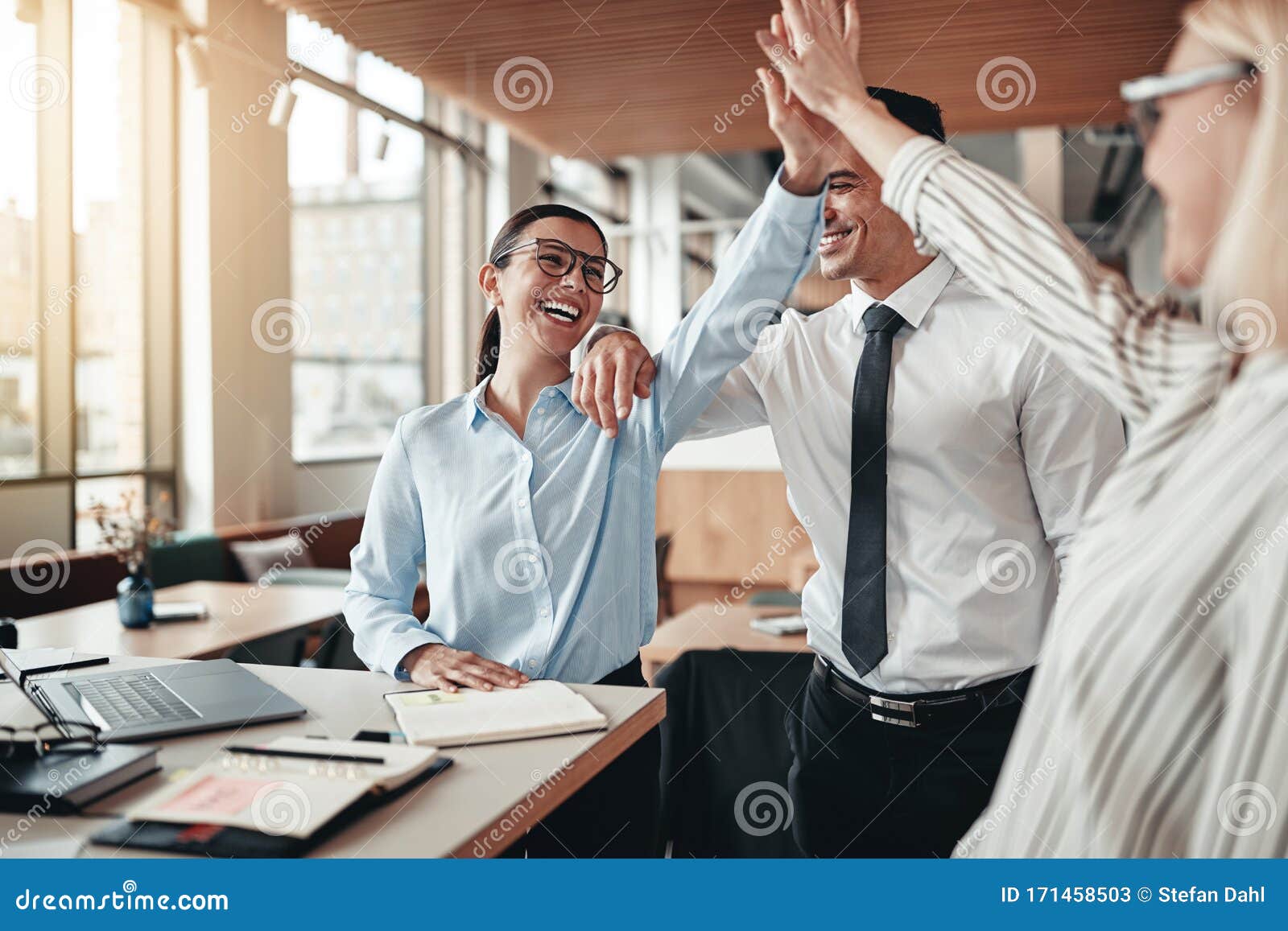 laughing businesspeople high fiving together in an office