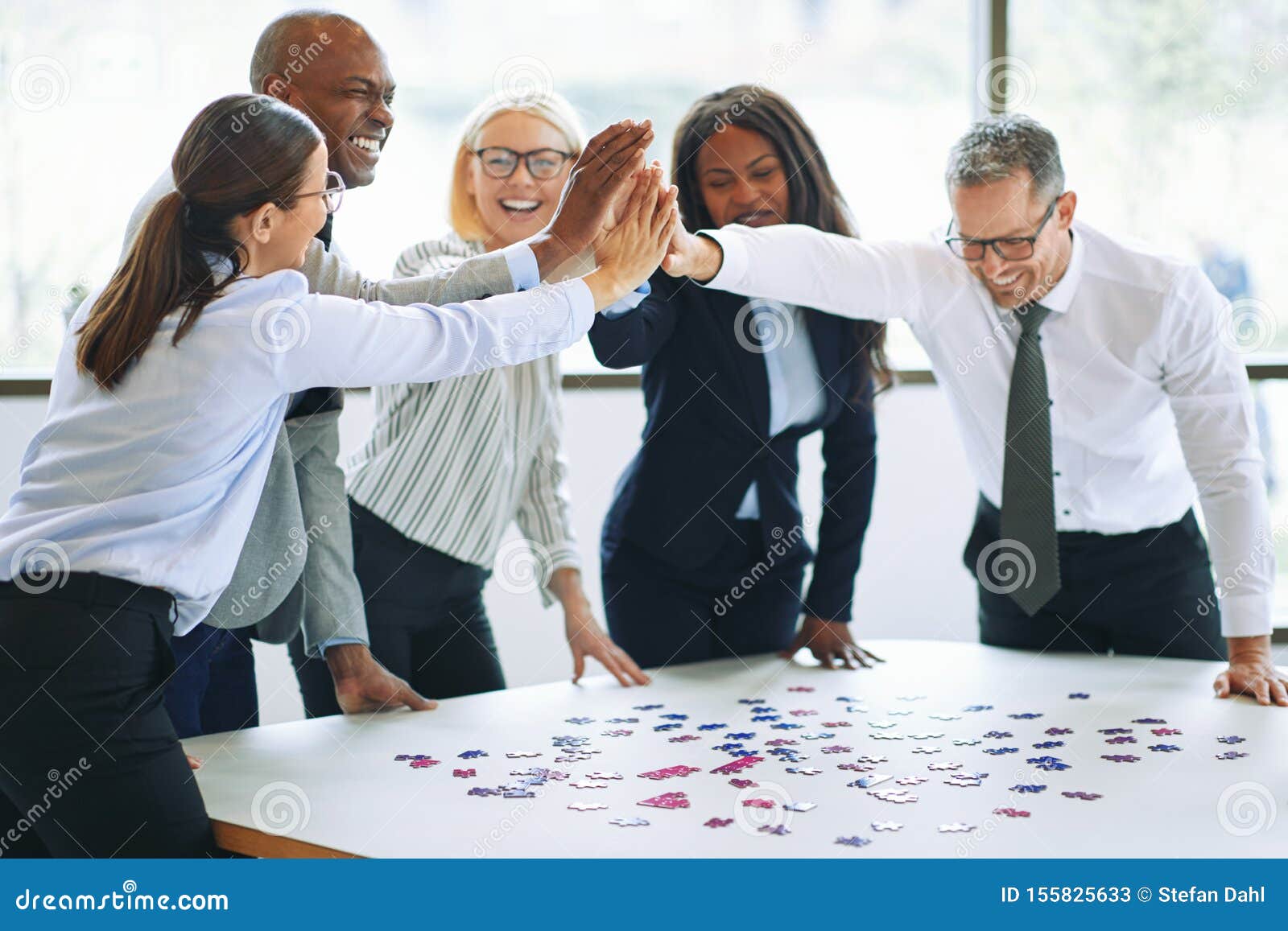 laughing businesspeople high fiving together while solving a jig