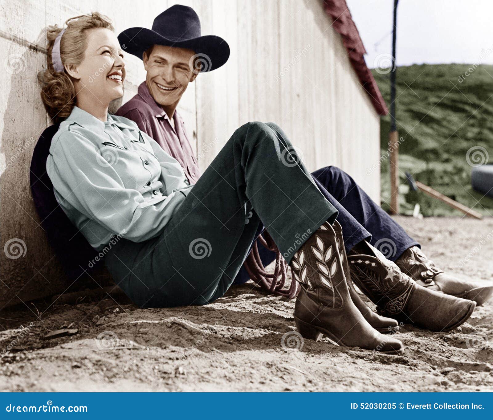 laughing couple in western attire sitting on the ground