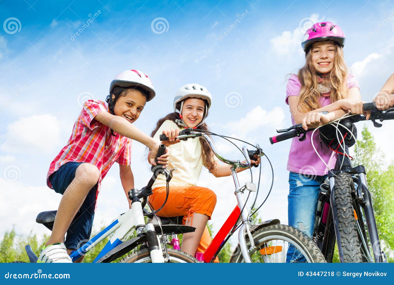 laughing kids in helmets hold bike handle-bars
