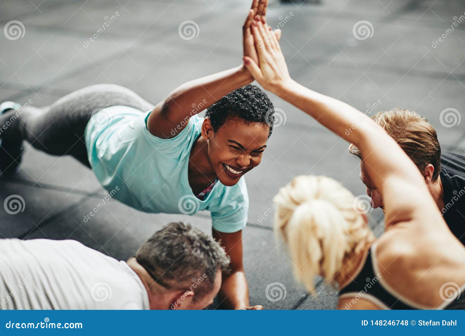 laughing women high fiving while planking in a gym class