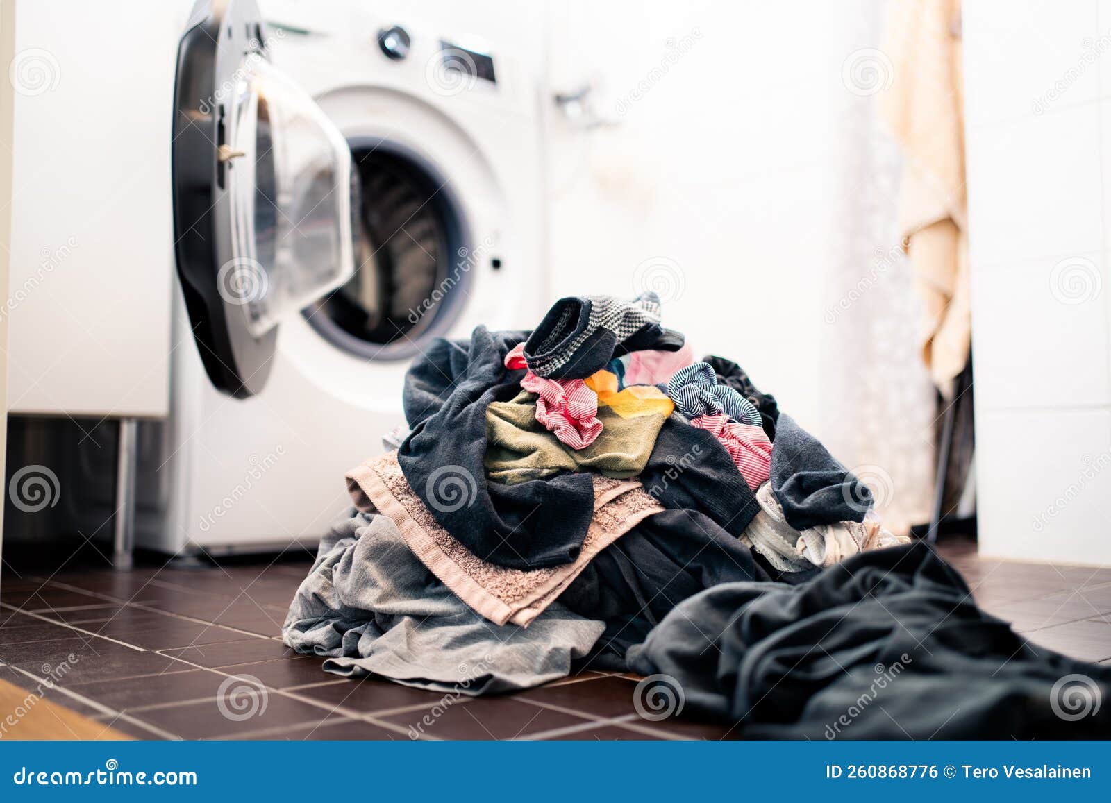Laundry Day. Washing Machine in the Background, Pile of Dirty Clothes on the Floor Stock Photo