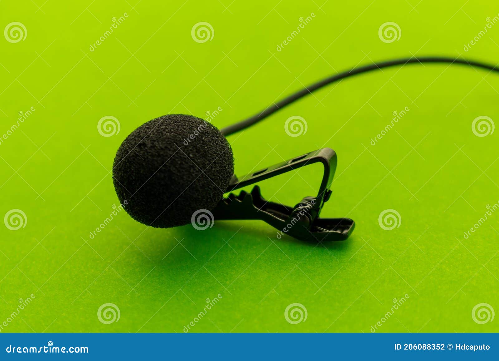 lavalier or lapel microphone on a green surface, very close-up. the details of the grip clip or bra and the sponge against the