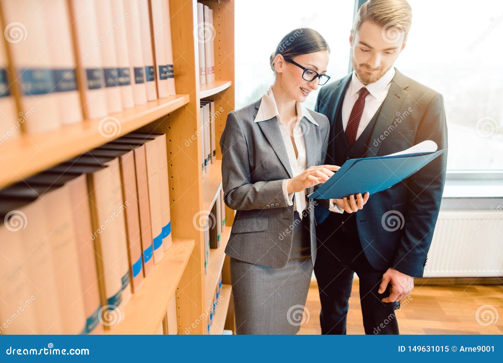 lawyers in library of law firm discussing strategy in a case holding file