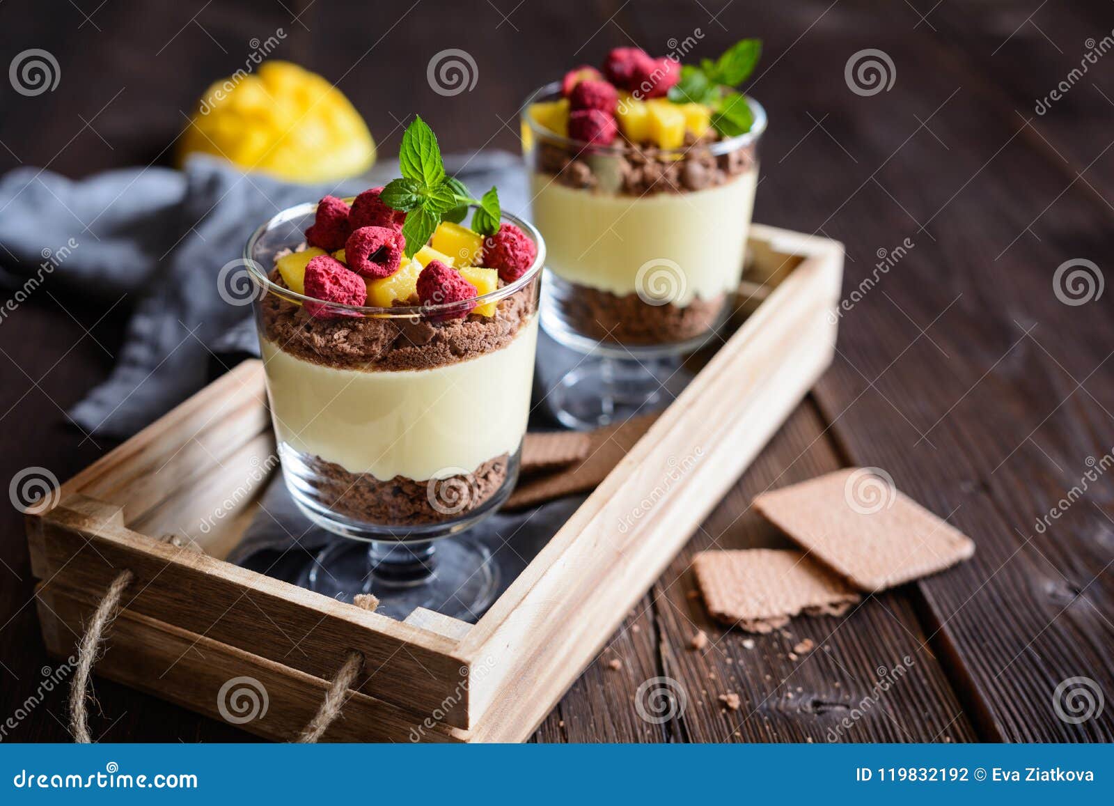 layered mango dessert with cream cheese, crushed biscuits and freeze dried raspberries