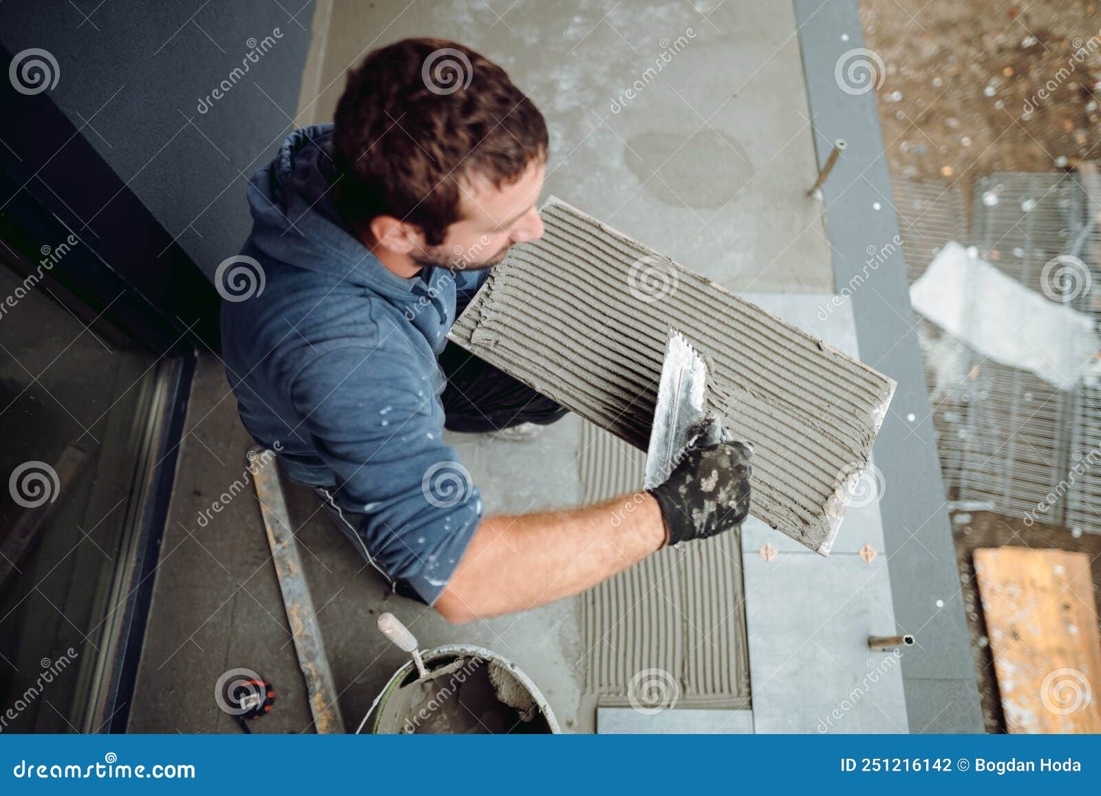 Worker Placing Ceramic Floor Tile in Position Over Adhesive Stock Photo