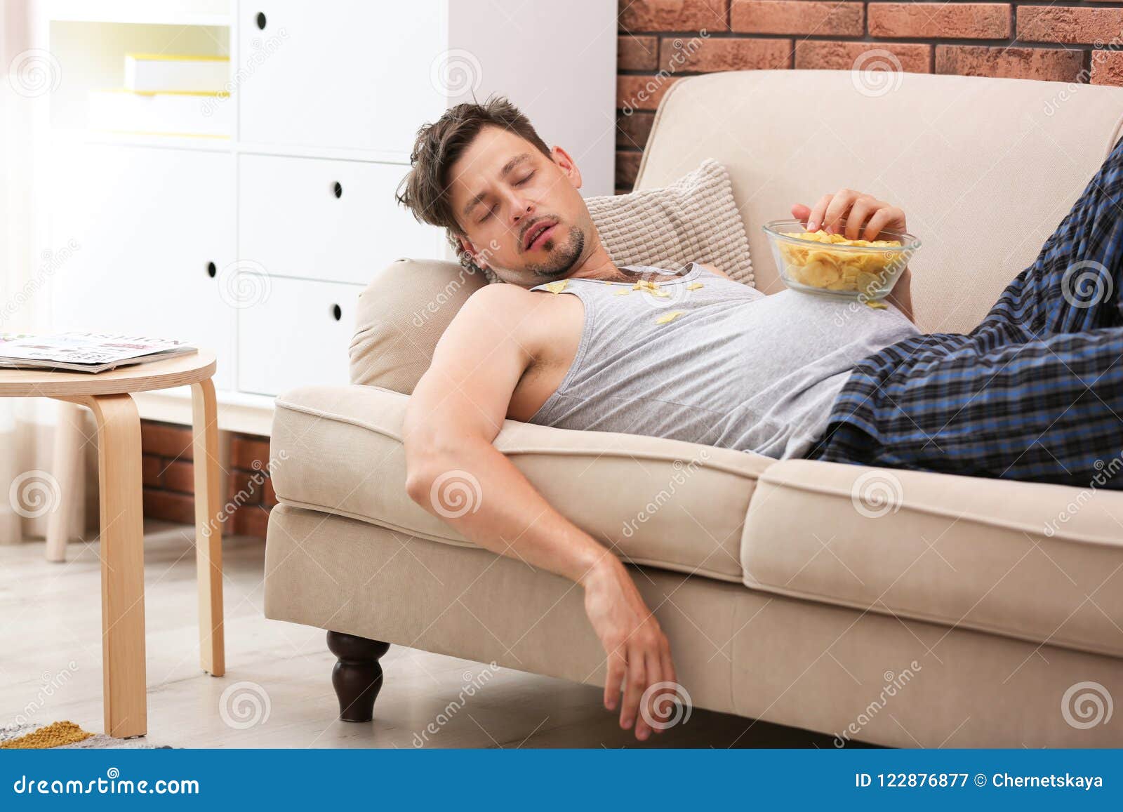 lazy man with bowl of chips sleeping on sofa
