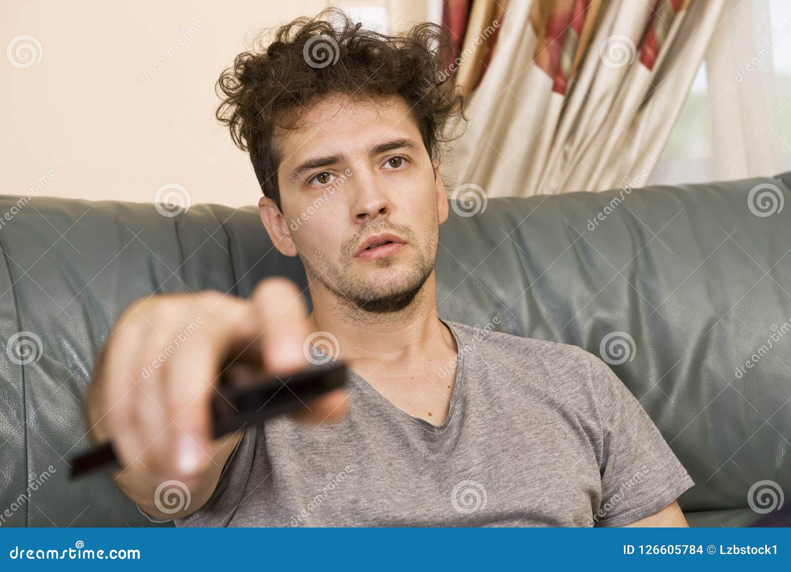 A Young Man Watches Television and Changes Channels while Relaxing