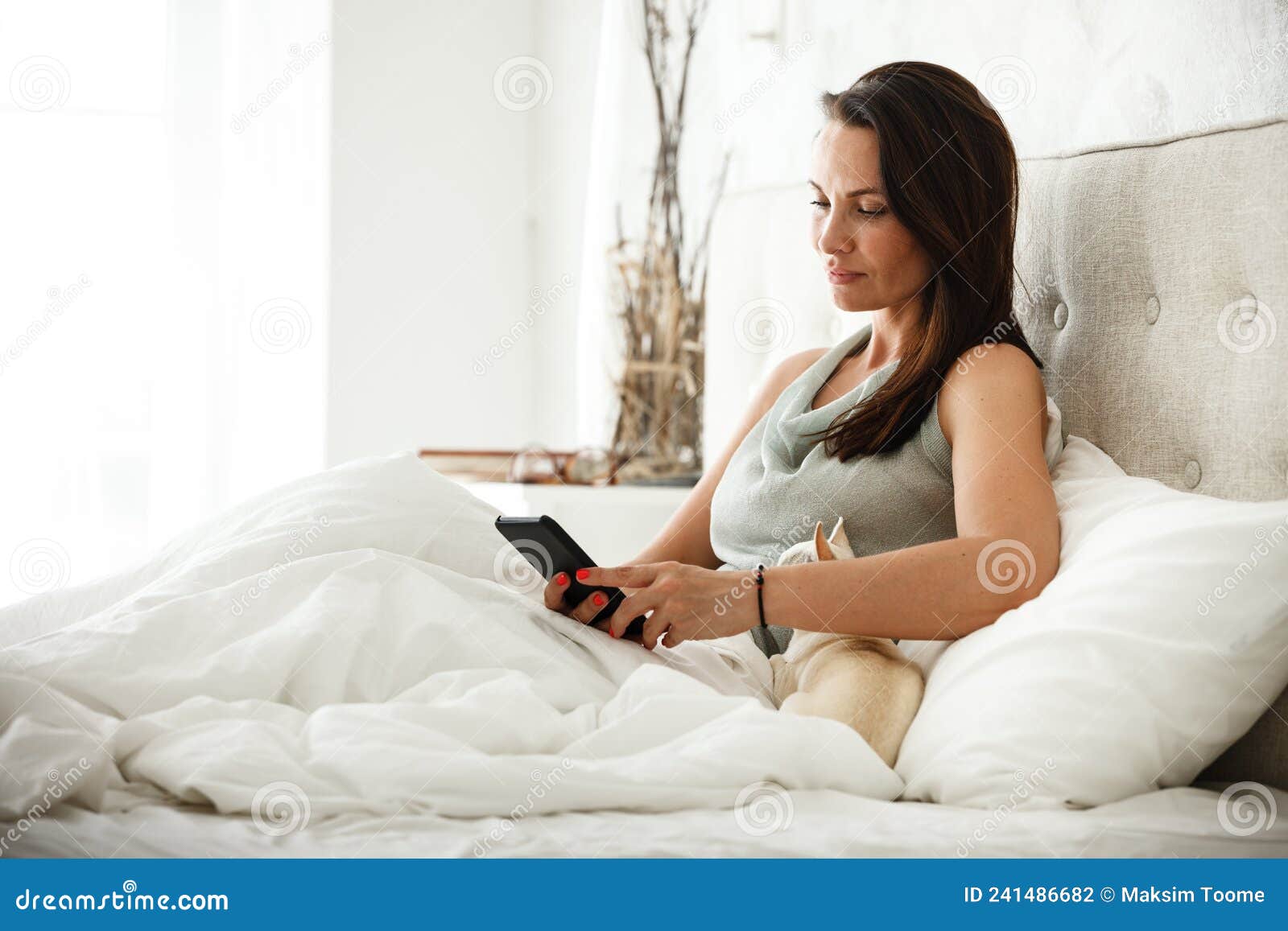 Lazy Morning Concept Beautiful Happy Woman Wakes Up In Bed And Surfes 