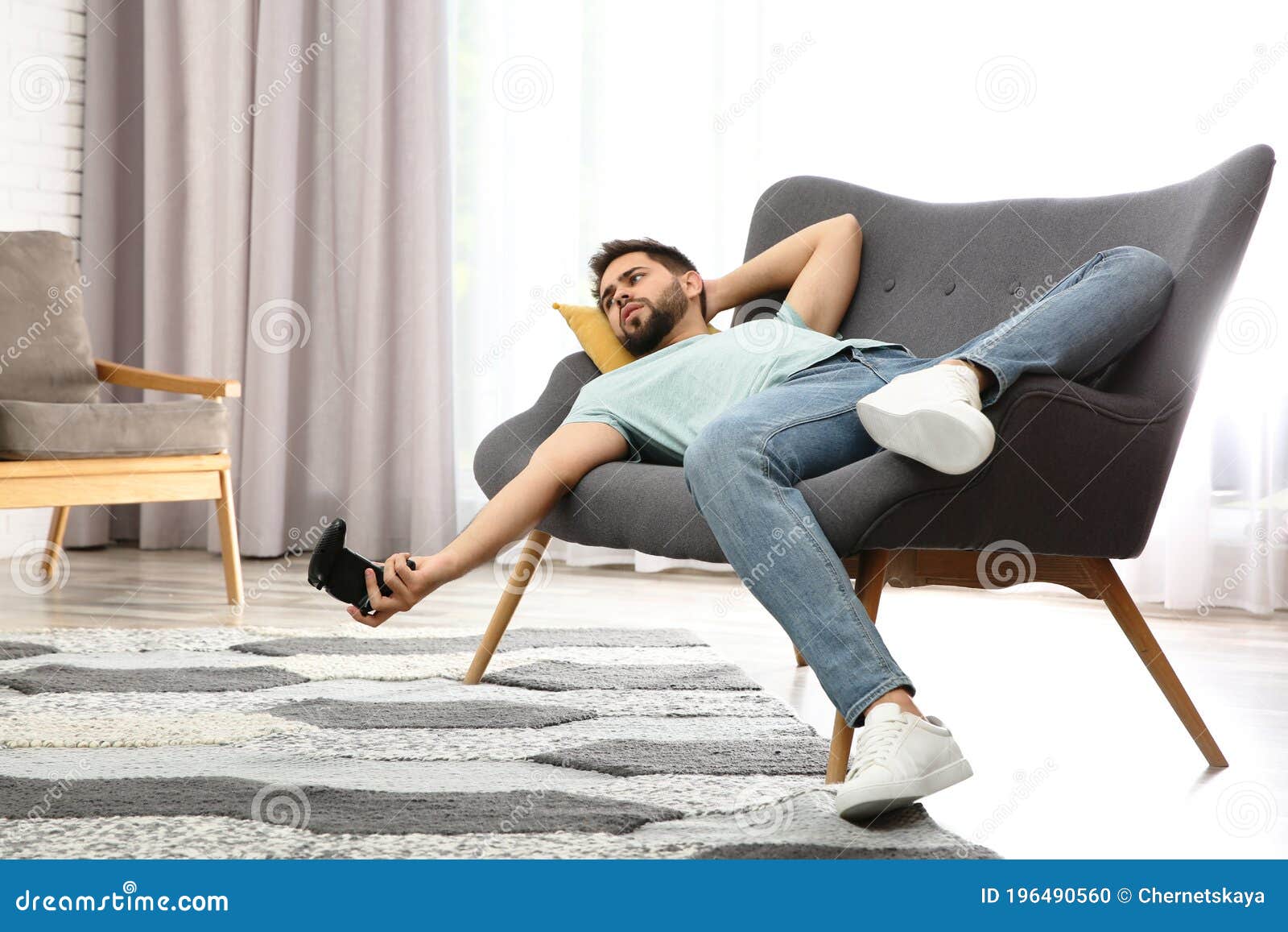 lazy man playing video game while lying on sofa at home