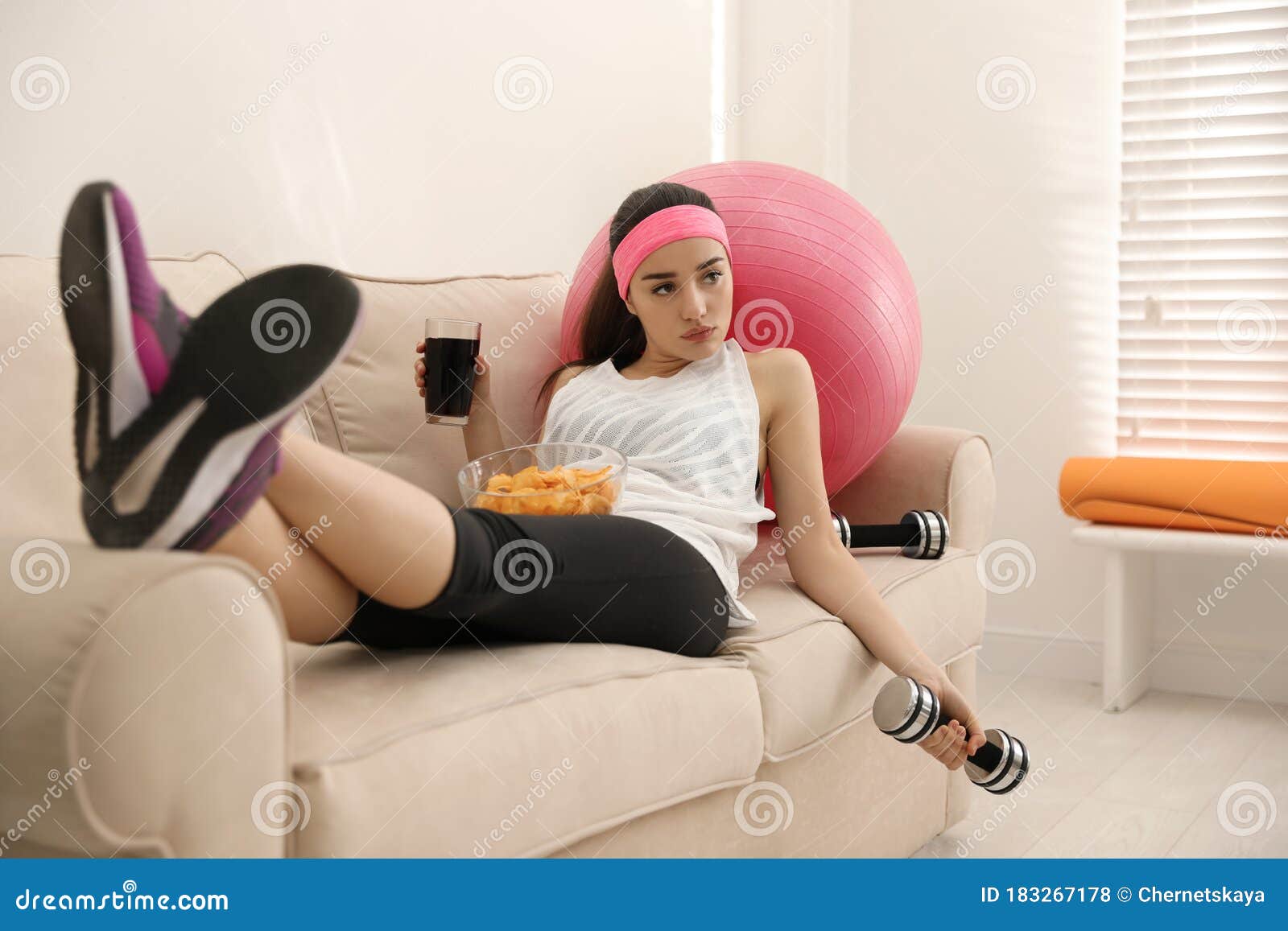 lazy woman with sport equipment and junk food at home