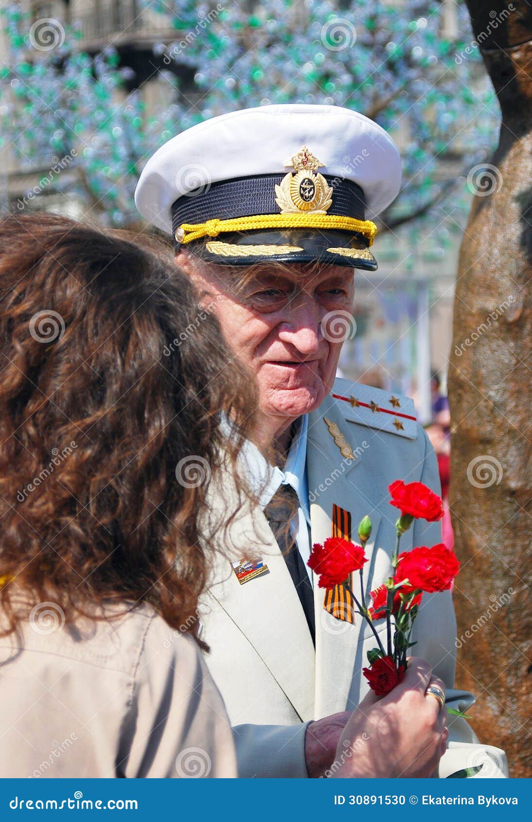 Le combattant reçoit des fleurs. Une femme donne les fleurs rouges d'oeillet à un combattant. Célébration de Victory Day le 9 mai 2013 à Moscou.