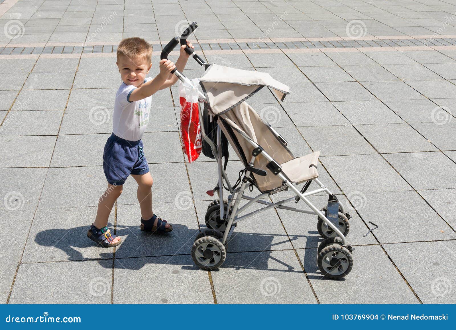 Le Garçon Pousse Une Voiture D'enfant Photo stock - Image du frais,  heureux: 103769904