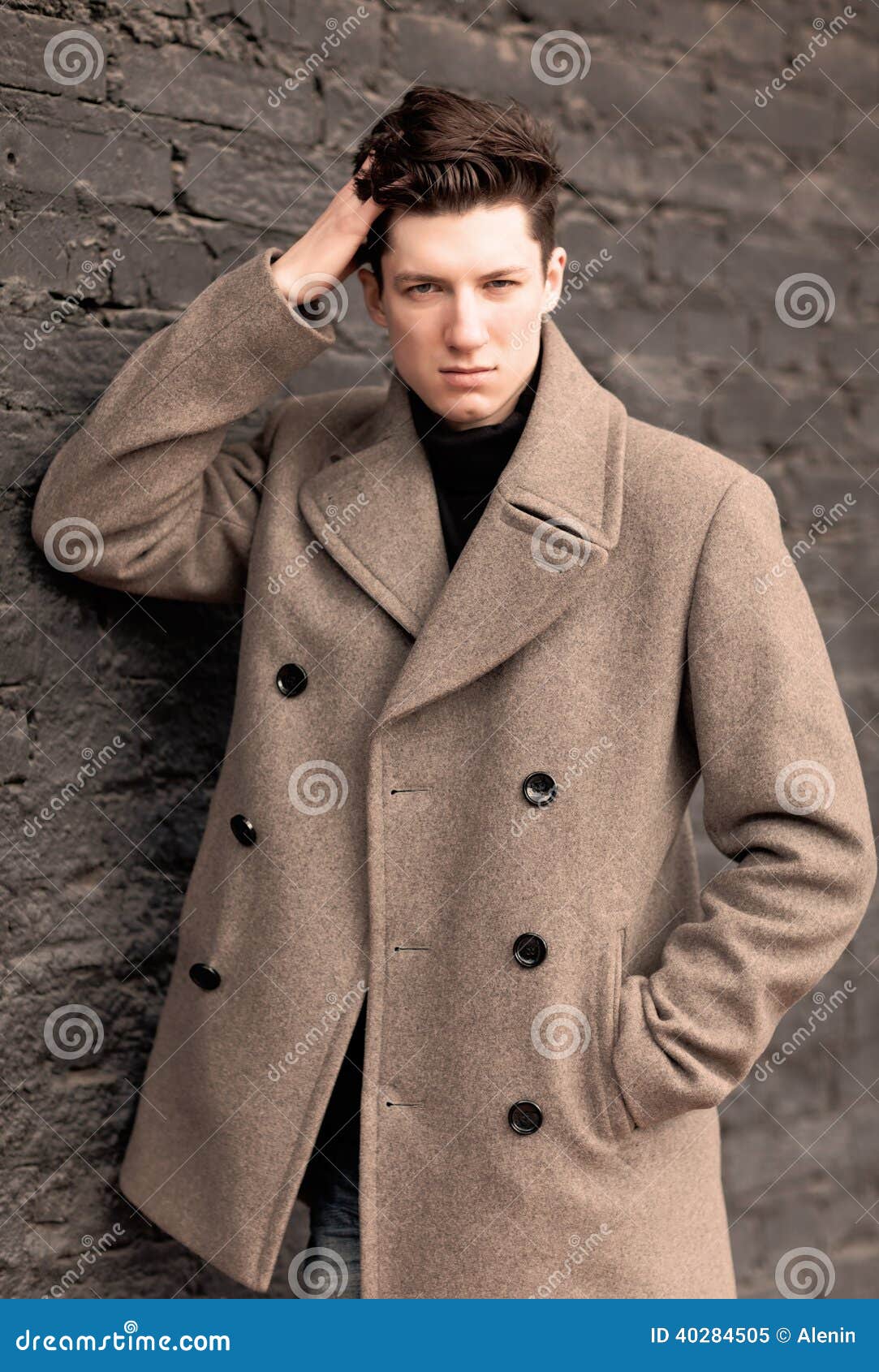 le mod u00e8le de jeune homme dans un manteau pose  u00e0 un mur de briques  modifi u00e9 la tonalit u00e9 image
