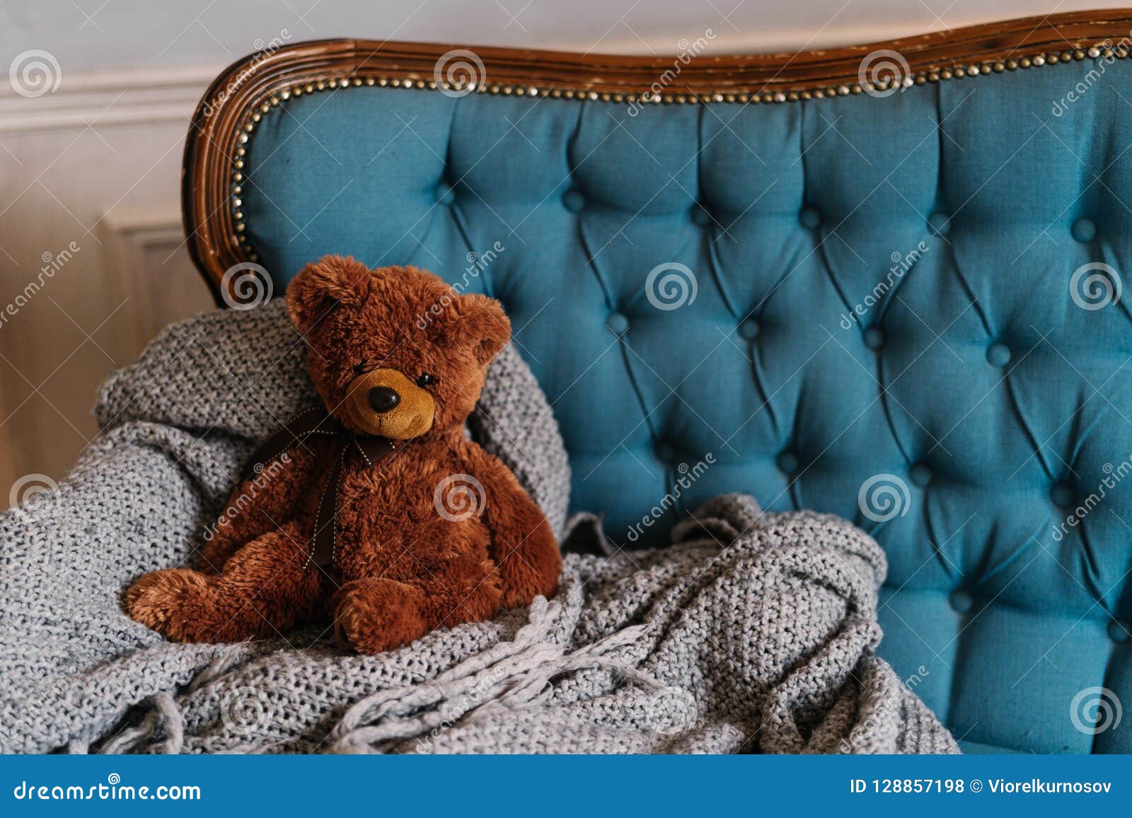 Le nounours de Brown concernent le sofa de luxe Agrément et atmosphère domestique Jouet sur la couverture grise au divan jouet pelucheux mou pour l'enfant