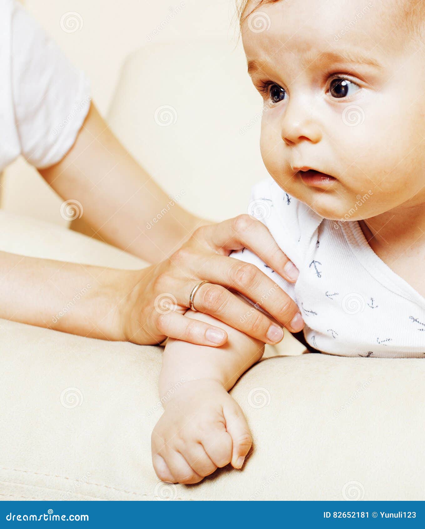 Le petit bébé garçon mignon d'enfant en bas âge jouant sur la chaise, mère assure tenir la main, fin de concept de personnes de mode de vie