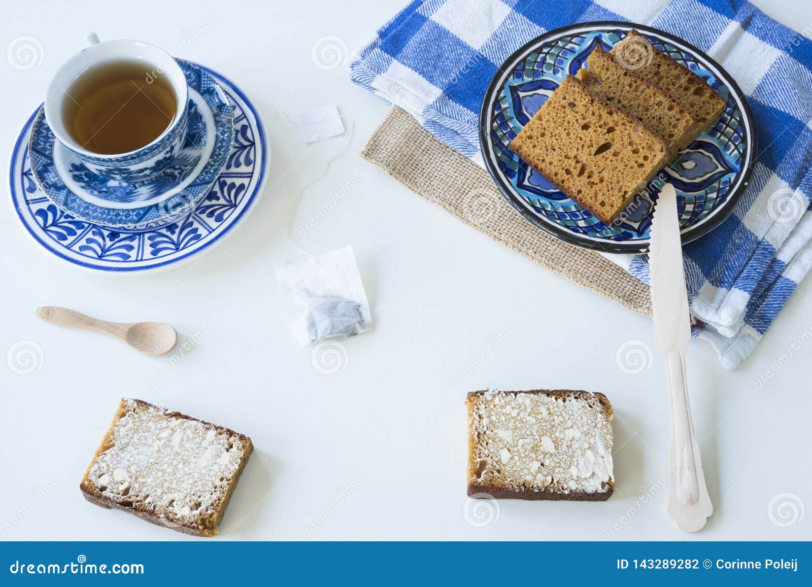 Le petit déjeuner avec néerlandais traditionnel épicé a durci l'ontbijtkoek ou le peperkoek appelé tasse de thé, fond blanc. Le petit déjeuner étendu plat avec du pain néerlandais typique a appelé l'ontbijtkoek ou le peperkoek du plat et de la serviette Tasse bleue de thé, fond blanc