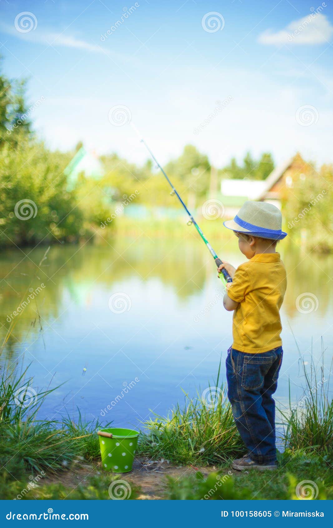 Petit Garçon Pêchant En Salopette Depuis Un Quai Sur Un Lac Ou Un Étang.  Enfant Avec Une Canne À Pêche Au Bord De L'eau. Jeune Pêcheur En Voyage De  Pêche, Vue Arrière.