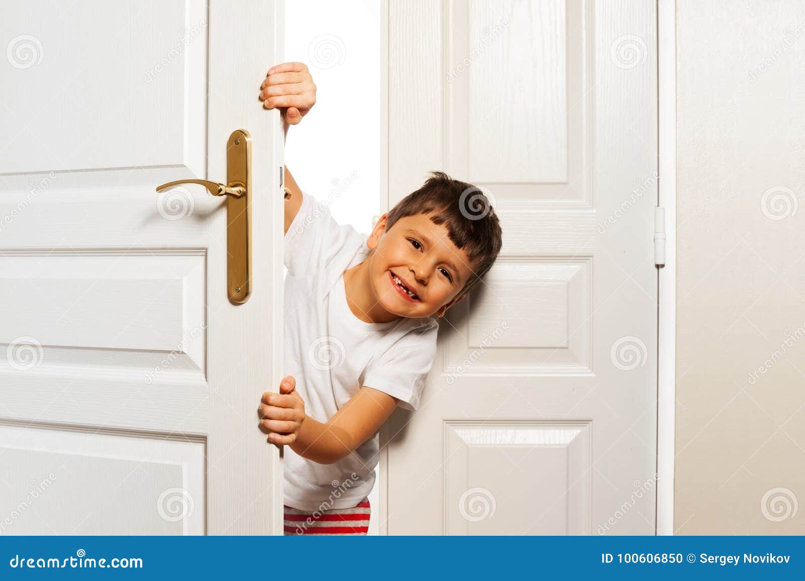 Le Petit Garçon Regarde Derrière La Porte De Pièce Avec Le Sourire Photo  stock - Image du indoors, coup: 100606850