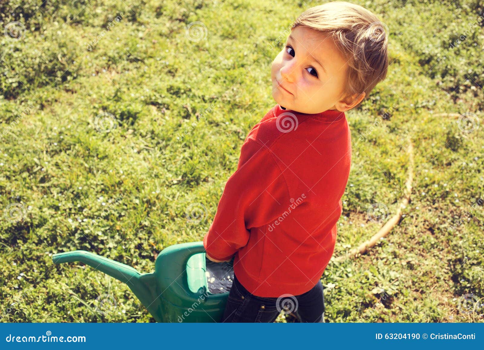 Le petit jardinier portent l'arroser-pot lourd dans le jardin