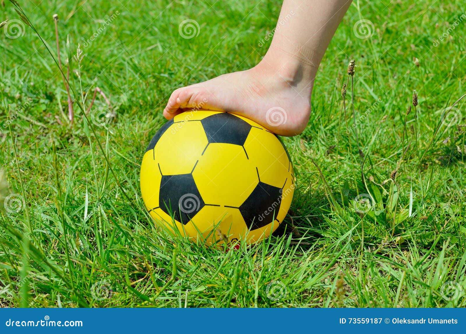 Le Pied Déchaussé Et Un Ballon De Football D'enfants Sur L'herbe