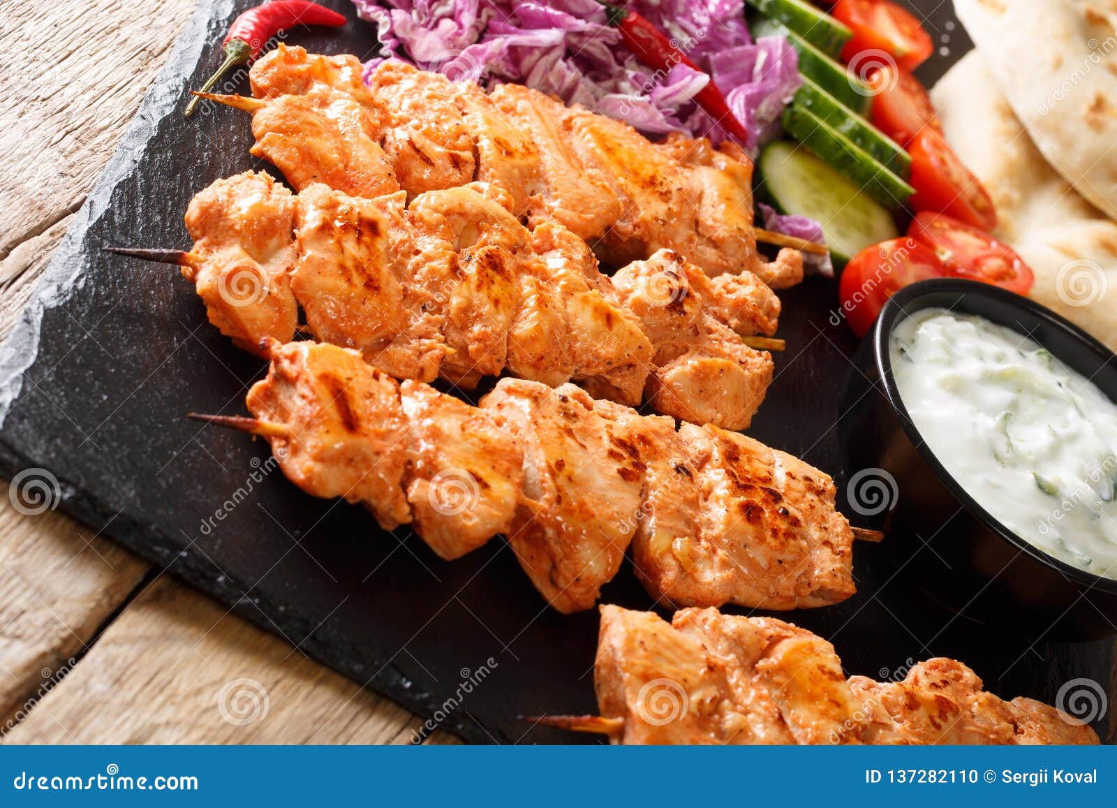 lebanese shish taouk tawookwith fresh vegetables, yogurt sauce and pita close-up. horizontal