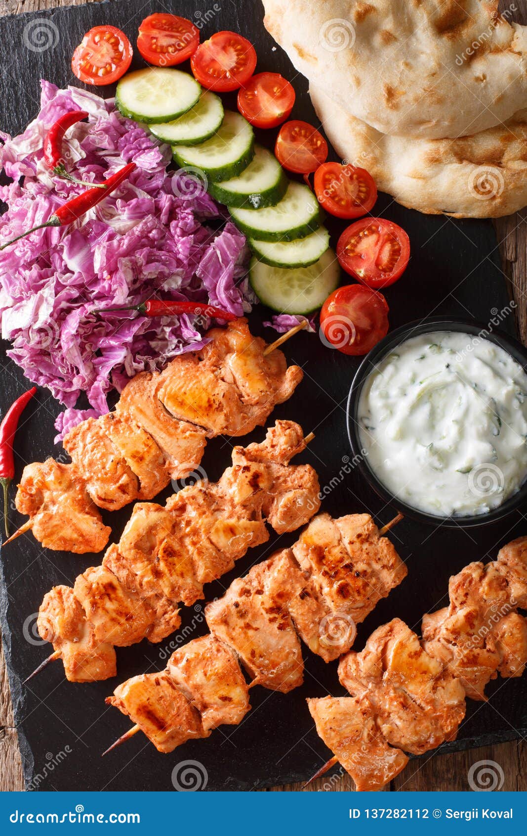 lebanese shish taouk tawookwith fresh vegetables, yogurt sauce and pita close-up. vertical top view