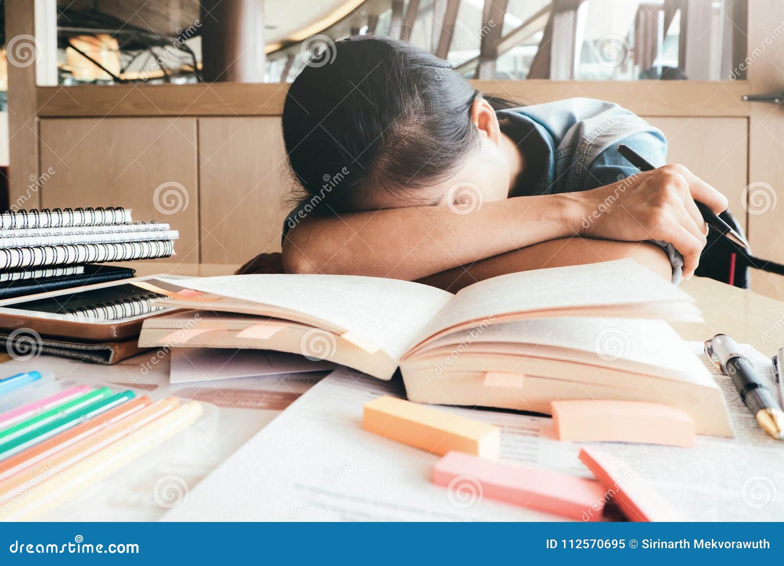 Lectura dura de la muchacha y el dormir en la biblioteca. Libros del primer y lectura dura de la muchacha cansada del estudiante y el dormir en la biblioteca