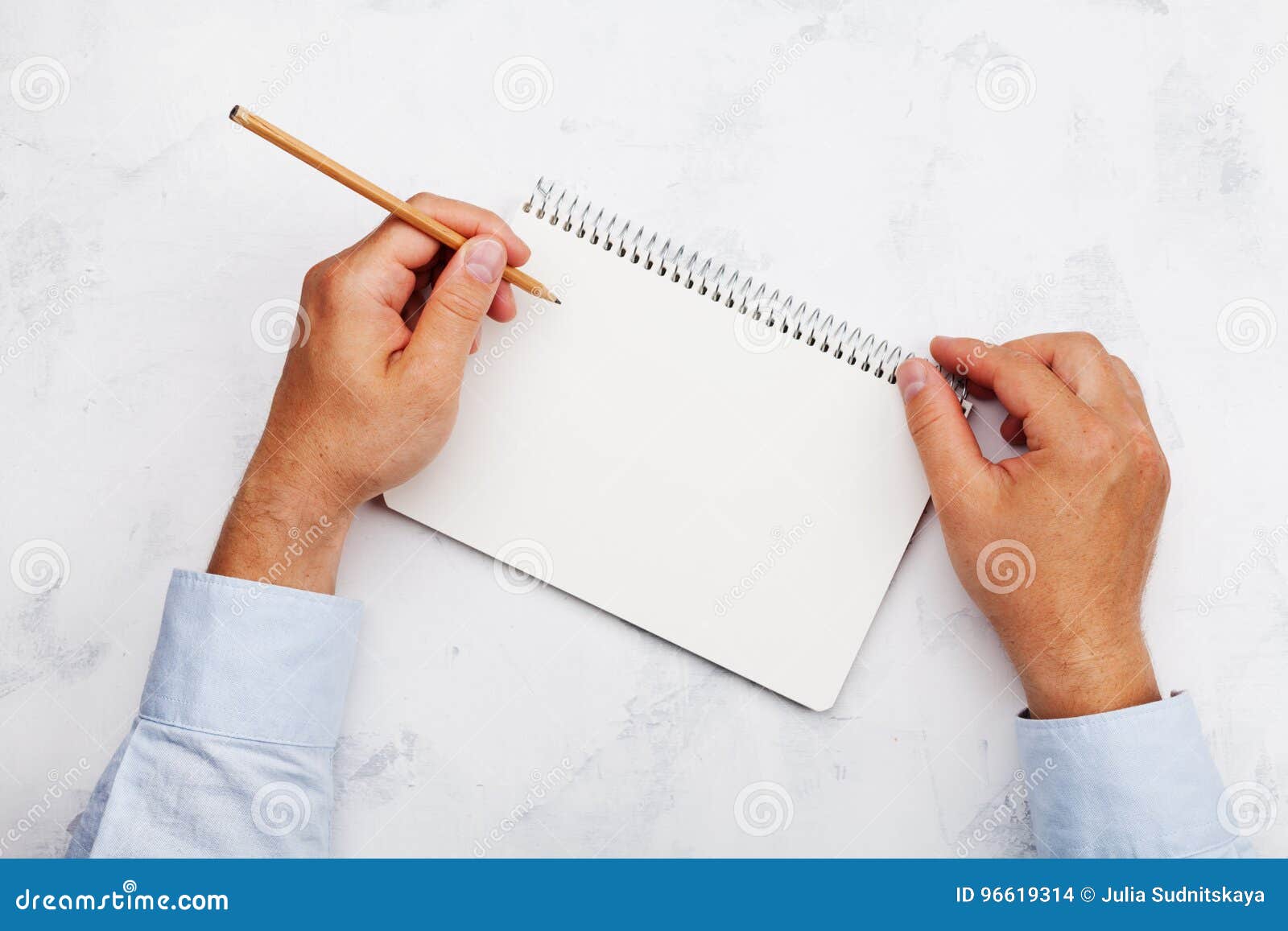 lefty writes in clean notebook on white table top view. international lefthanders day.