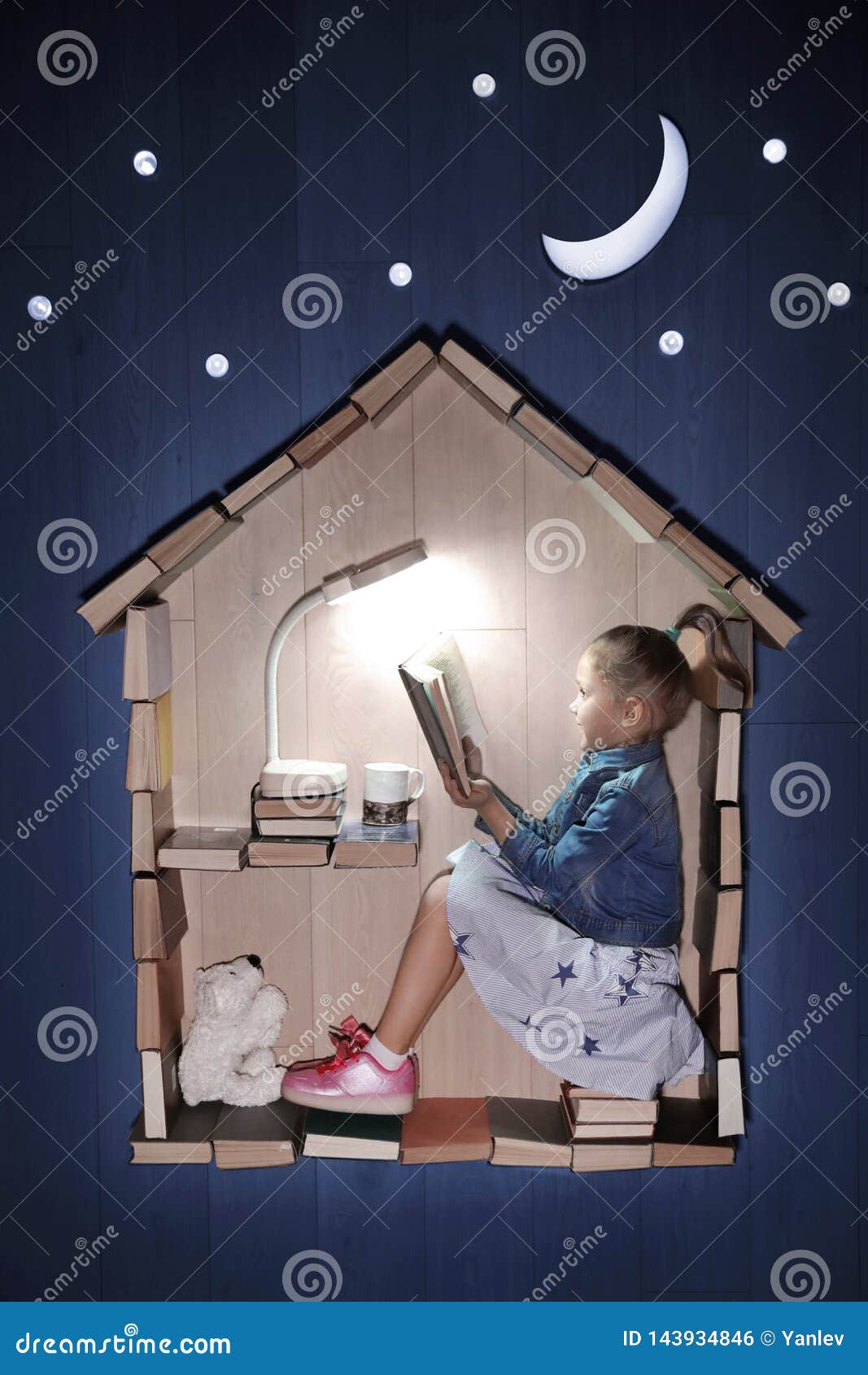 Leggiamo pi?. Foto concettuale di una ragazza che legge un libro in una casa dei libri Fuori - della notte, della luna e delle stelle