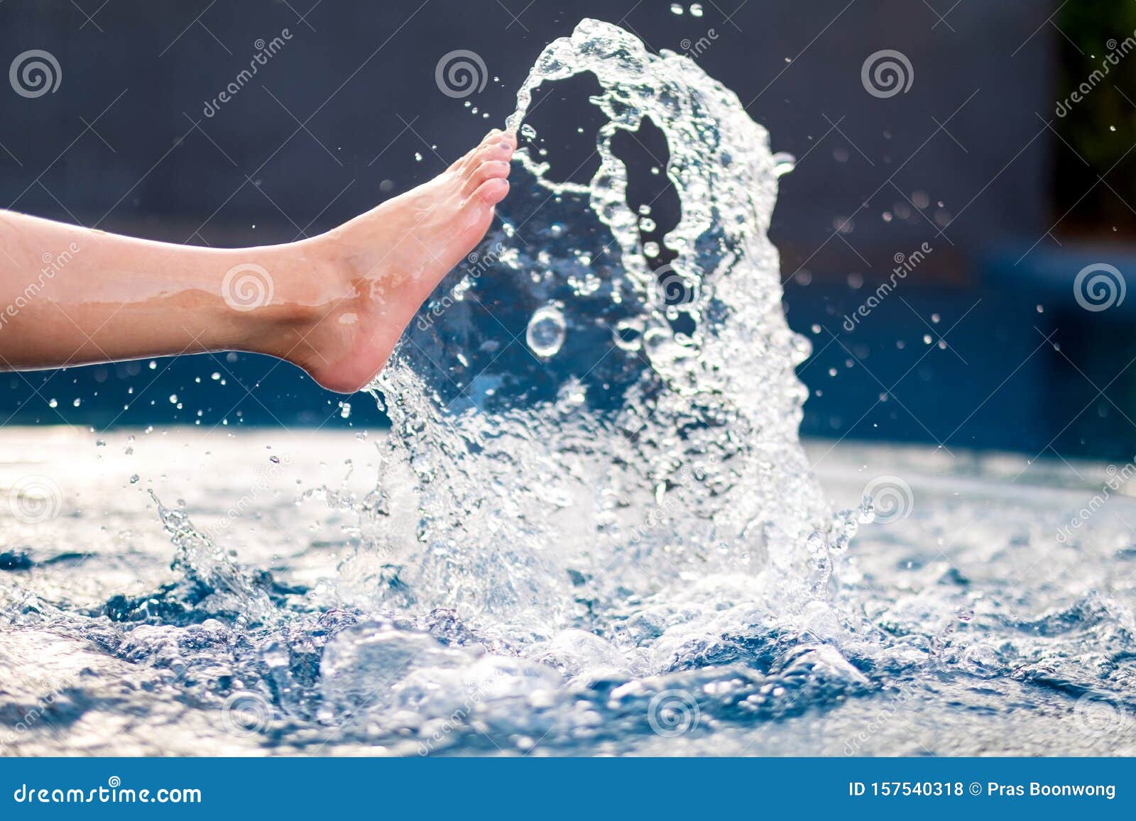 Legs and Bare Feet Kicking and Splashing Water in the Pool Stock Photo