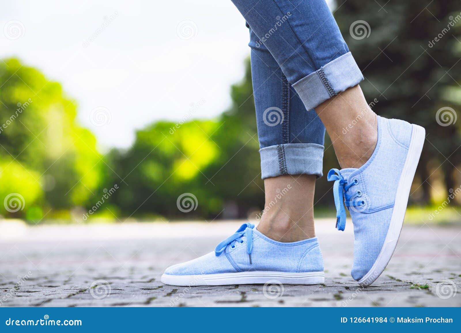 Legs of a Girl in Jeans and Blue Sneakers on a Sidewalk Tile, a Young ...