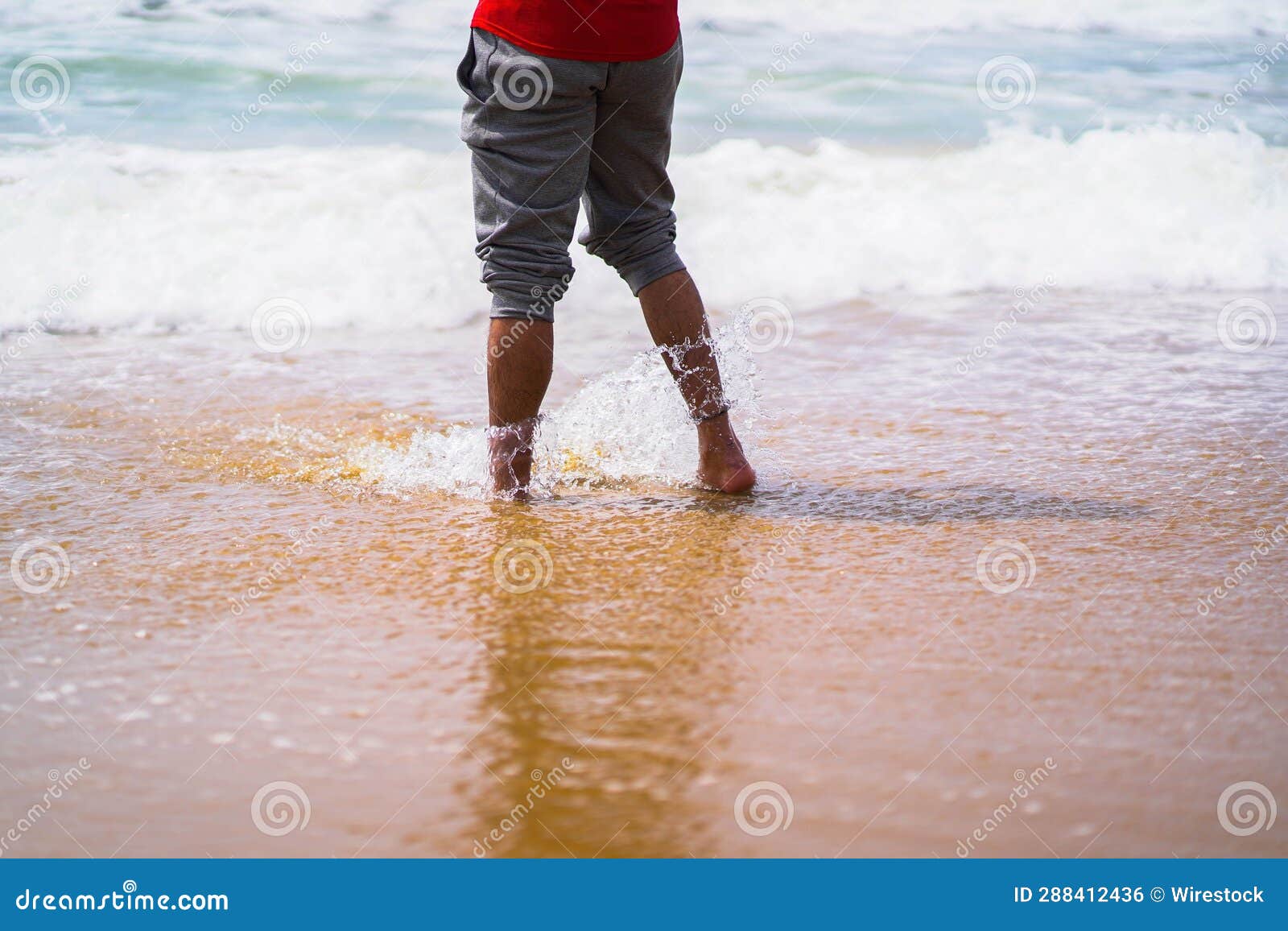 Legs of a Person Standing on the Sandy Shoreline Against the Lapping ...