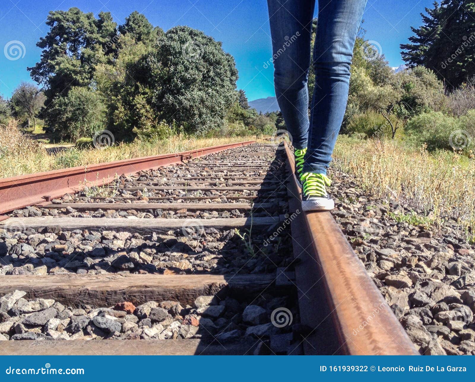 Woman laying between railroad tracks - Stock Photo - Dissolve