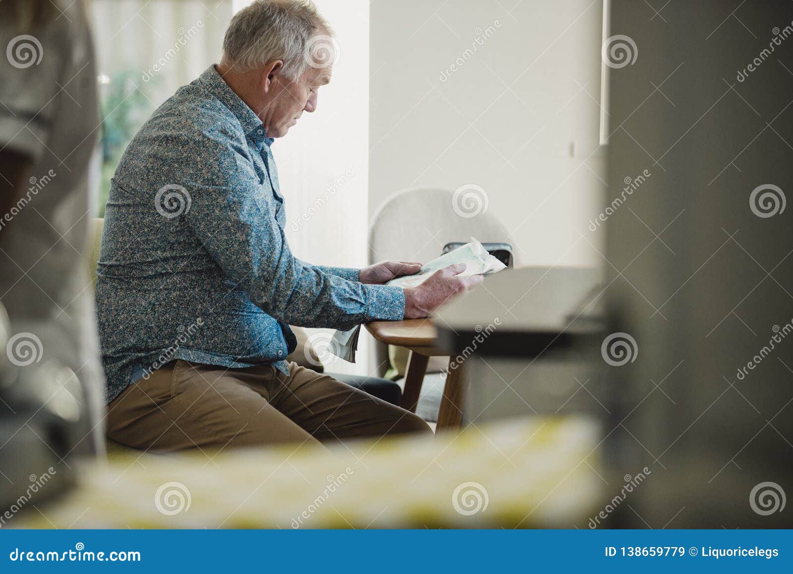 Leitura do homem superior na casa do cuidado. Os homens superiores do diabético estão sentando-se em uma mesa de jantar que leem um jornal quando sua equipe de tratamento preparar sua medicamentação