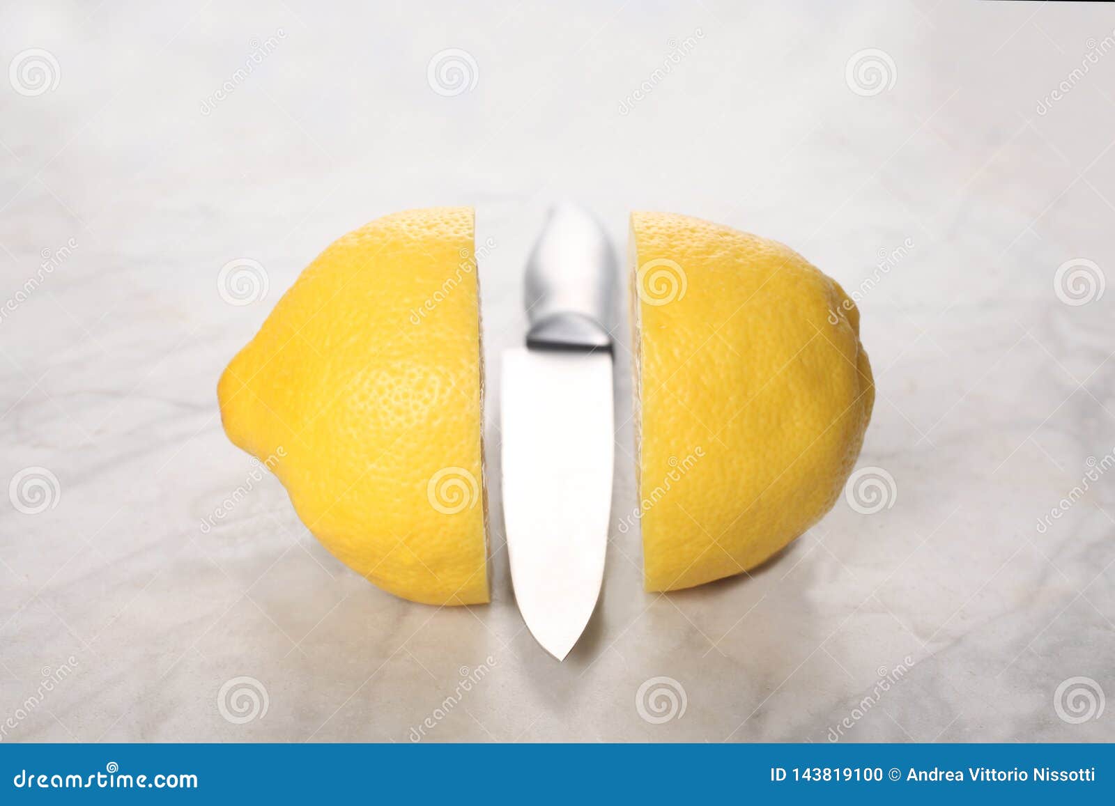 A Lemon Cut in Two Half and a Knife on a Marble Table with Copy Space