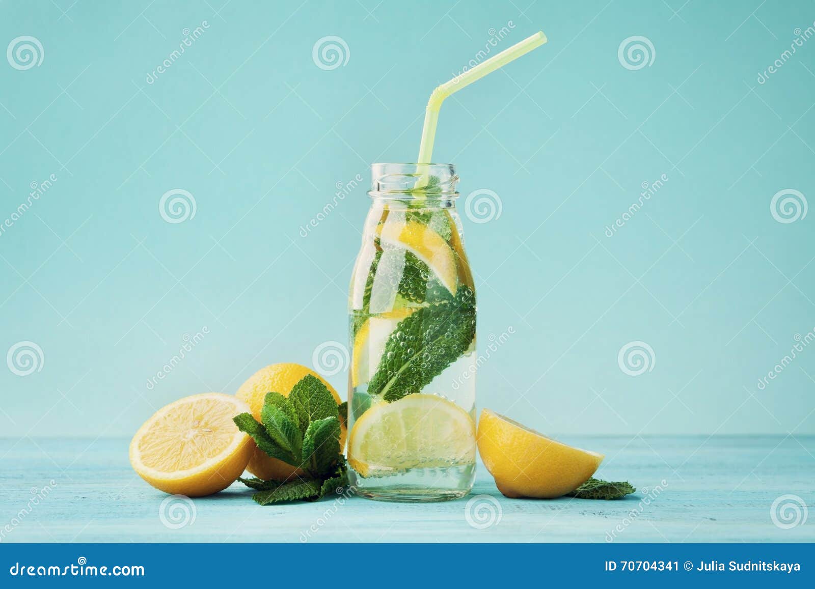 lemonade drink of soda water, lemon and mint in jar on turquoise background