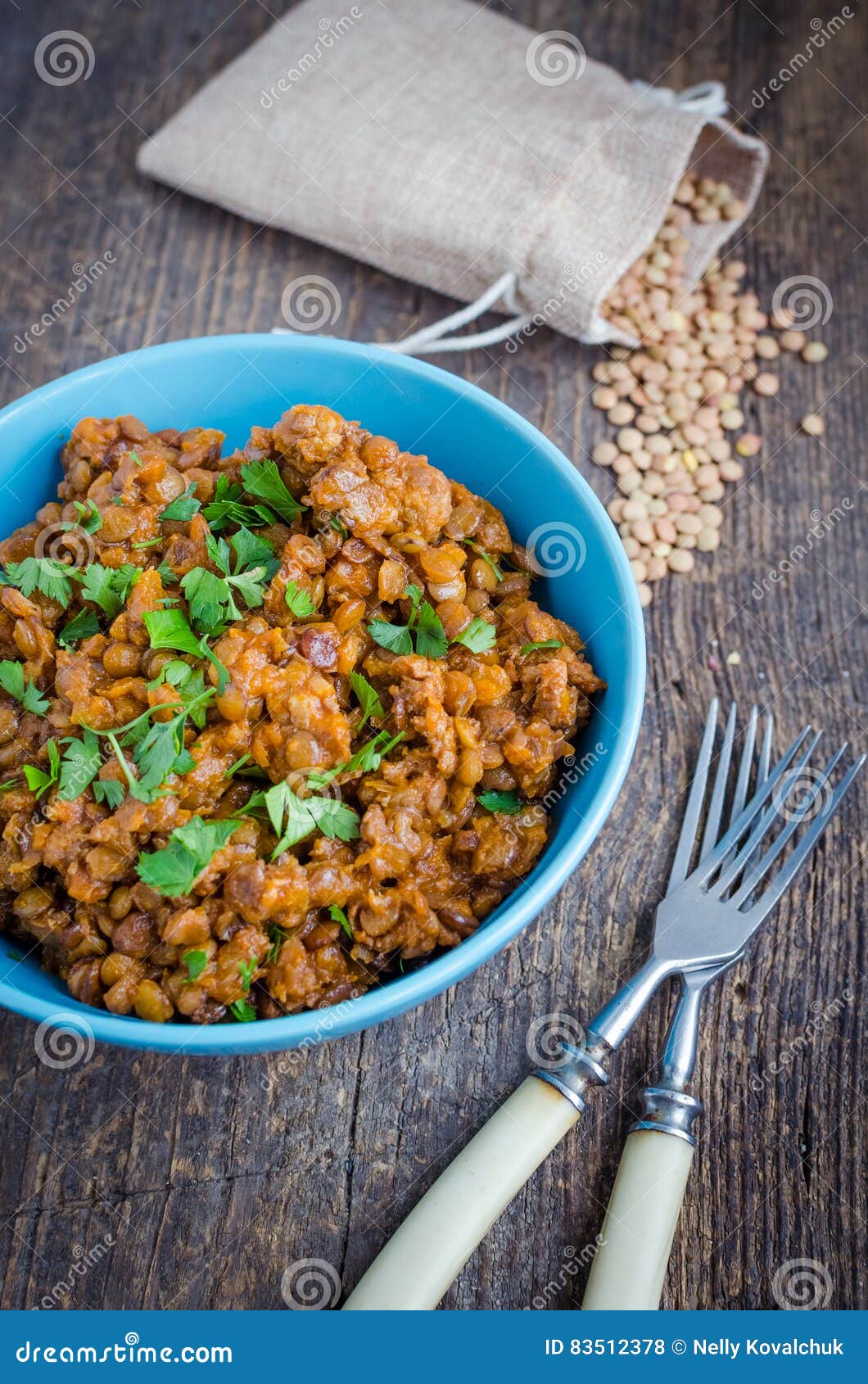 Lentil stew in a bowl with parsley. Frash lentil stew with bolognese sauce in a bowl with parsley on rustic wooden table. Italian food concept. Heathy vegetarian food. Selective focus.