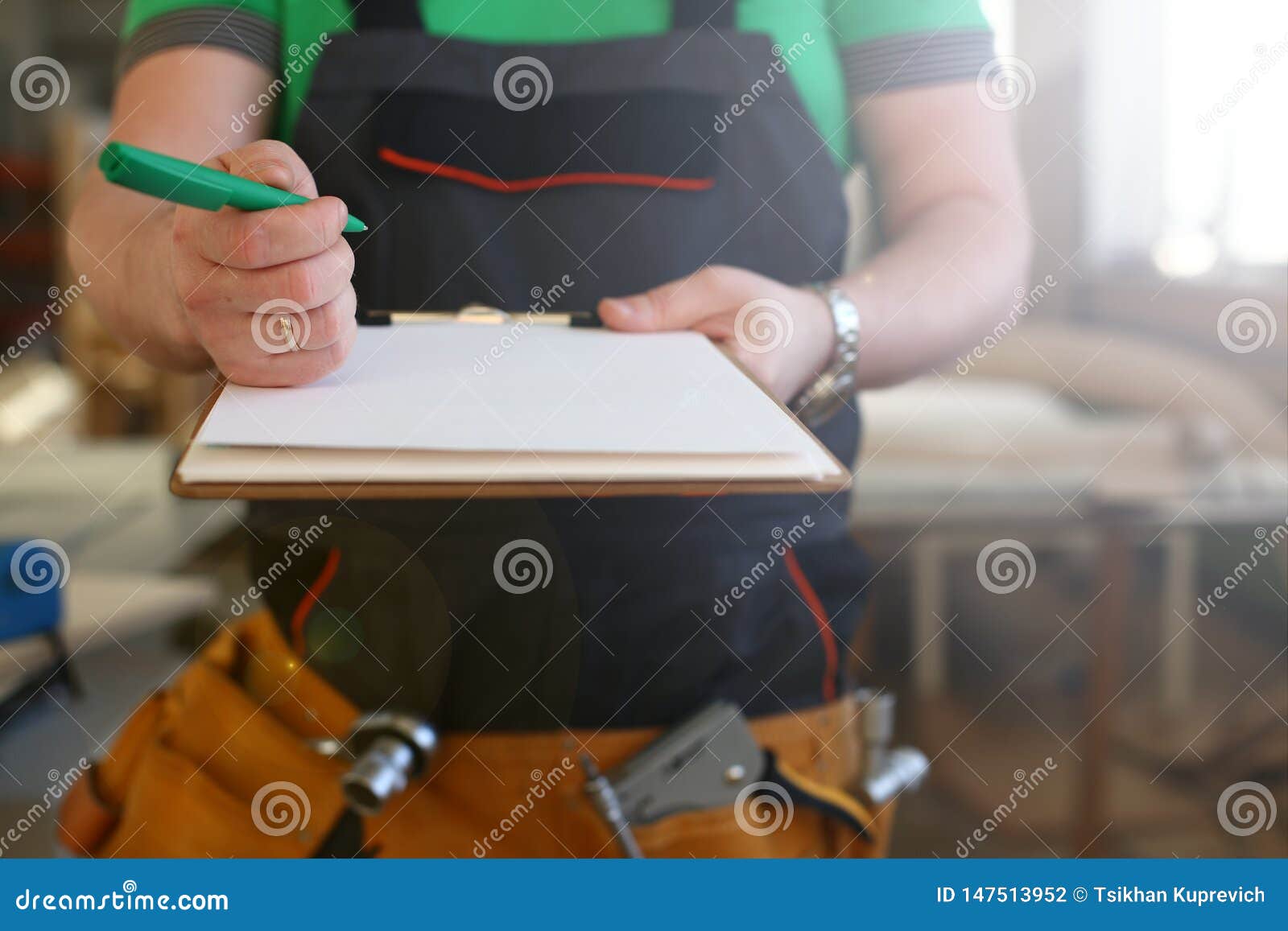 Les bras du travailleur offrent le presse-papiers avec le stylo vert. Arms of worker offer clipboard with green pen closeup. Manual job DIY inspiration improvement fix shop graphic joinery startup workplace idea designer career wooden bar ruler