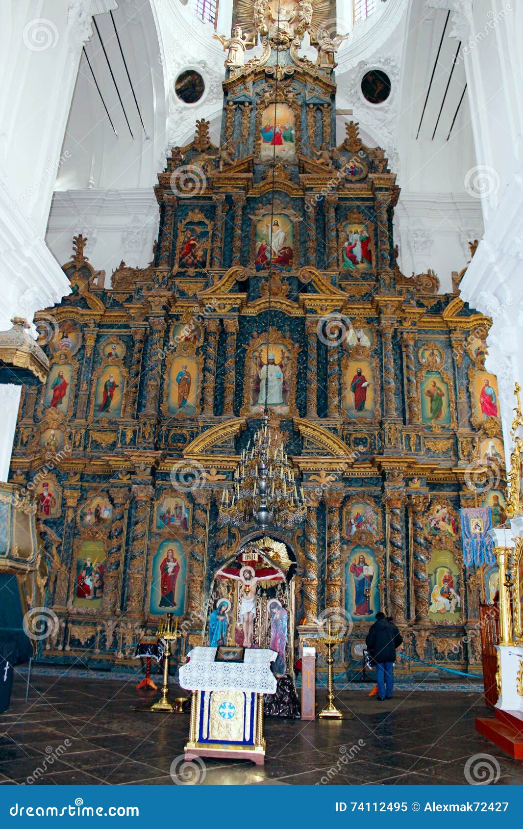 Les gens dans l'église près de la belle iconostase avec les icônes antiques ont placé dans le cadre en bois Oeuvre d'art religieuse dans l'église