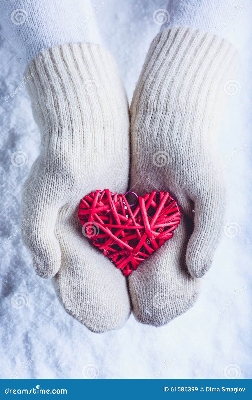 Les mains femelles dans le blanc ont tricoté des mitaines avec le coeur rouge romantique enlacé de vintage sur le fond de neige C. Les mains femelles dans le blanc ont tricoté des mitaines avec un coeur rouge romantique enlacé de vintage sur un fond de neige d'hiver Concept confortable d'amour et de St Valentine