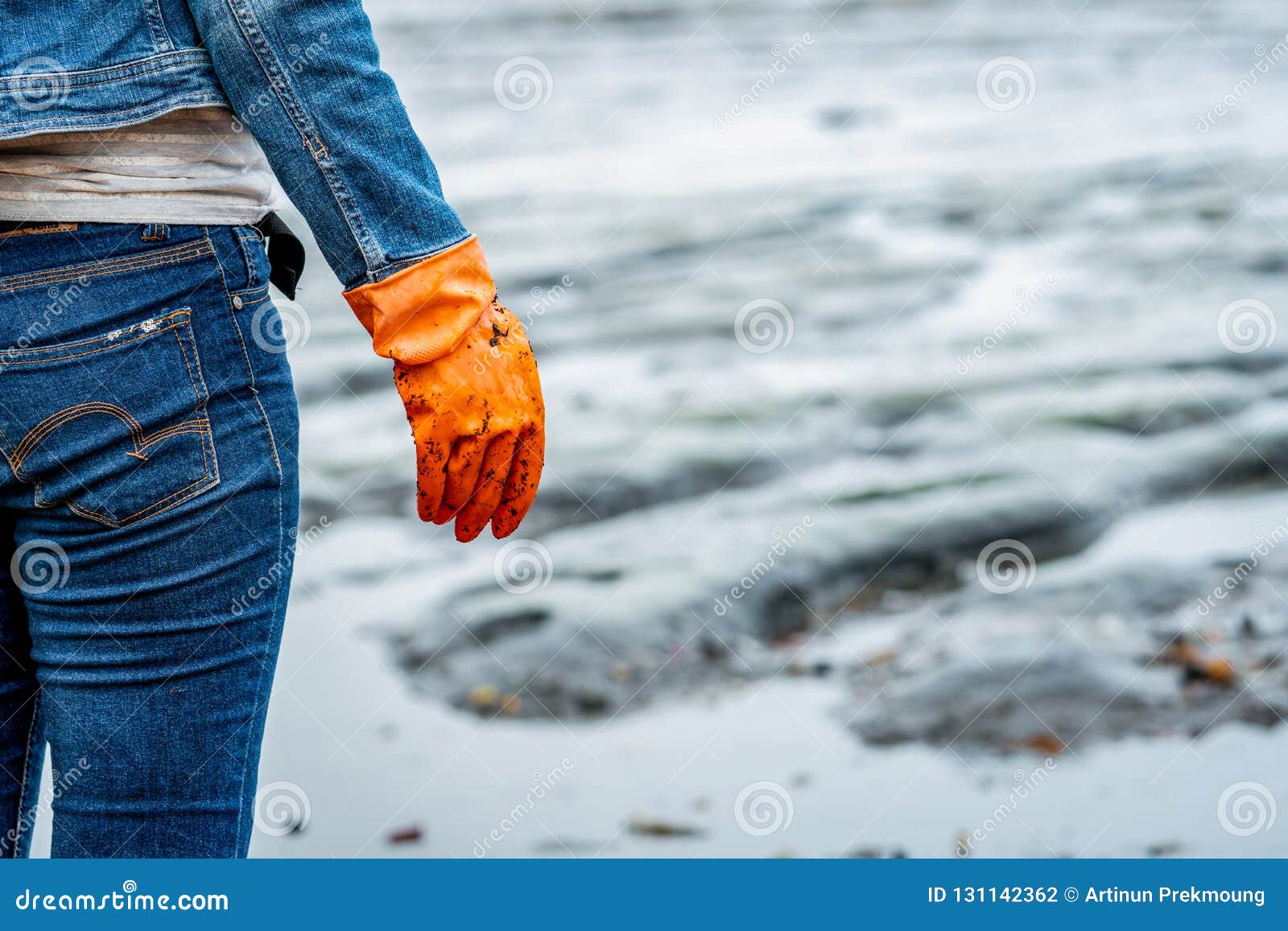 Les volontaires utilisent des jeans et de longues chemises gainées et portent les gants en caoutchouc oranges pour rassembler des déchets sur la plage Environnement de plage Femme nettoyant la plage Rangement des déchets sur la plage