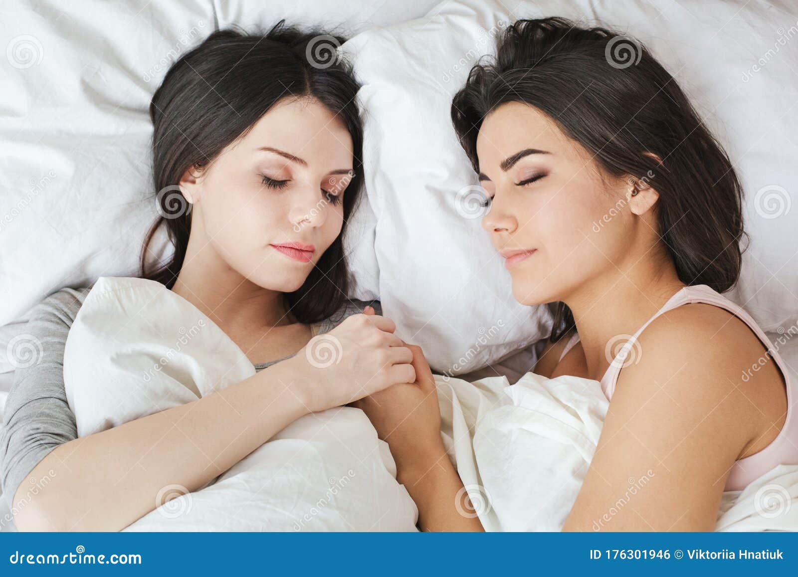 Lesbian Couple In Bedroom At Home Lying Under Blanket Holding Hands