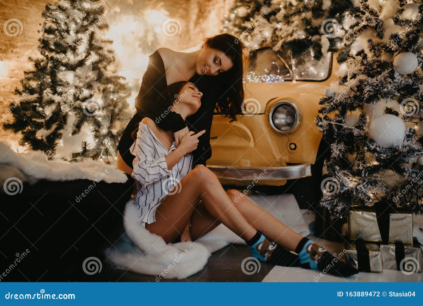 Lesbian Couple Hugs Against Background Of Christmas Decorations And