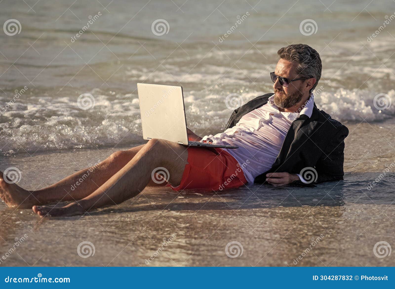 Letnia działalność biznesowa. biznesmen relaksujący się na plaży. biznesmen zrelaksowany na plaży. biznesmen w garniturze z laptopem latem. biznes marzy o letnim biznesie morskim. naładuj podróżując.