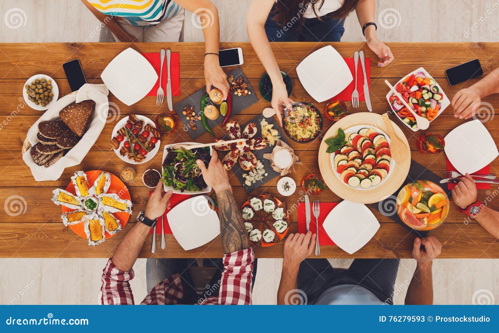 Leute essen gesunde Mahlzeiten am festlichen Tabellenabendessen. Leute essen gesunde Mahlzeiten am festlichen Tisch, der für Partei gedient wird Freunde feiern mit biologischem Lebensmittel auf Draufsicht des Holztischs Zu bemannen Frauendurchlaufteller