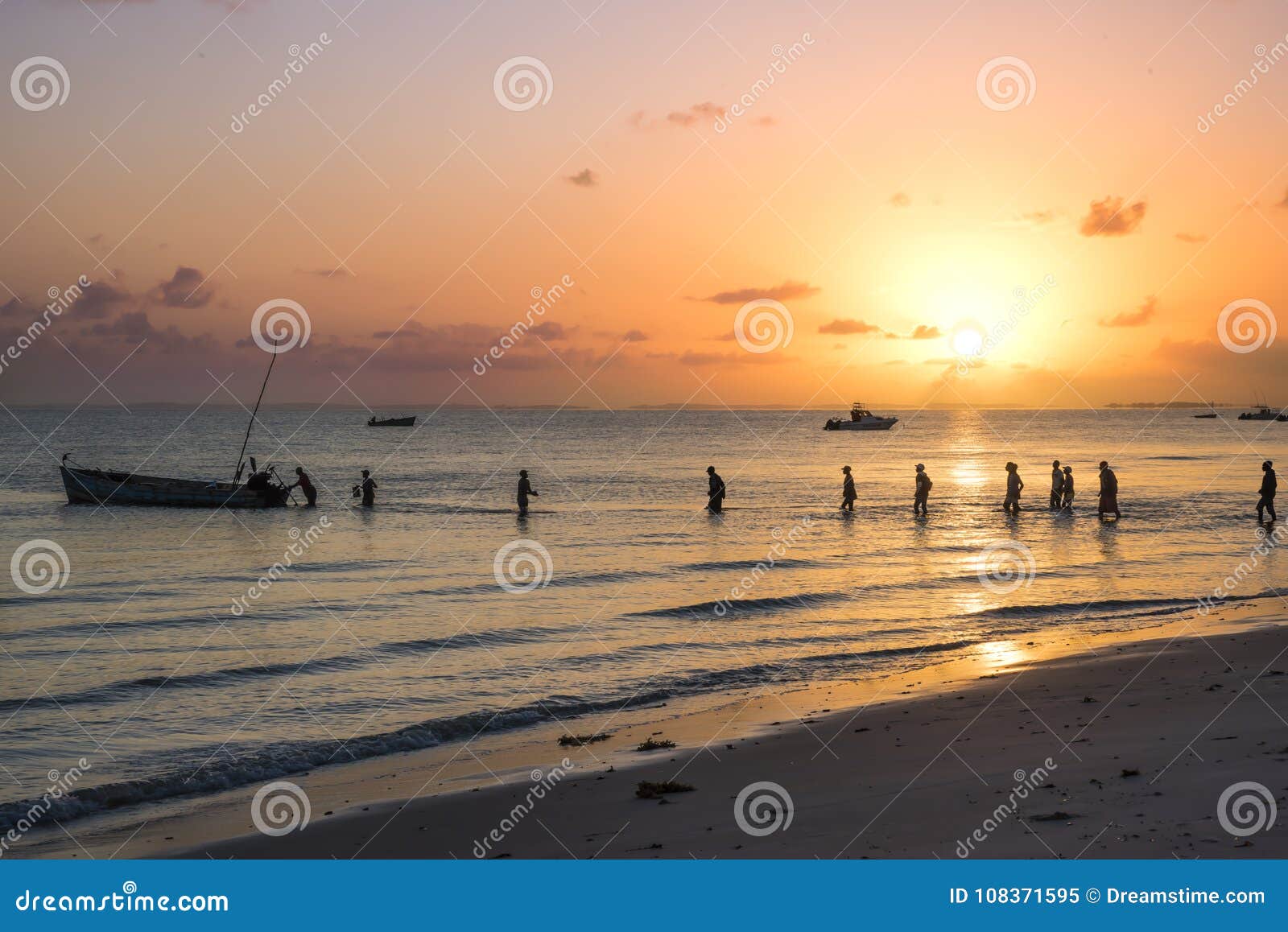 Lever de soleil au-dessus de la ligne de côte d'Inhassorro, Mozambique. Un beau lever de soleil plus d'à la ville côtière d'Inhassorro Un beau site en tant que pêcheur local pataugent dans l'étagère peu profonde d'océan pour monter à bord de leur dhaw