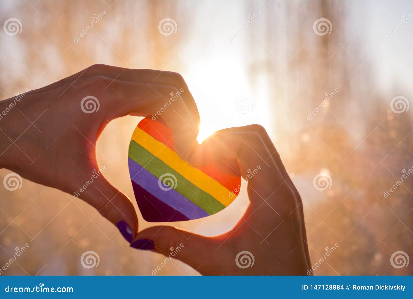 hands in the form of heart holds a heart painted like a lgbt flag